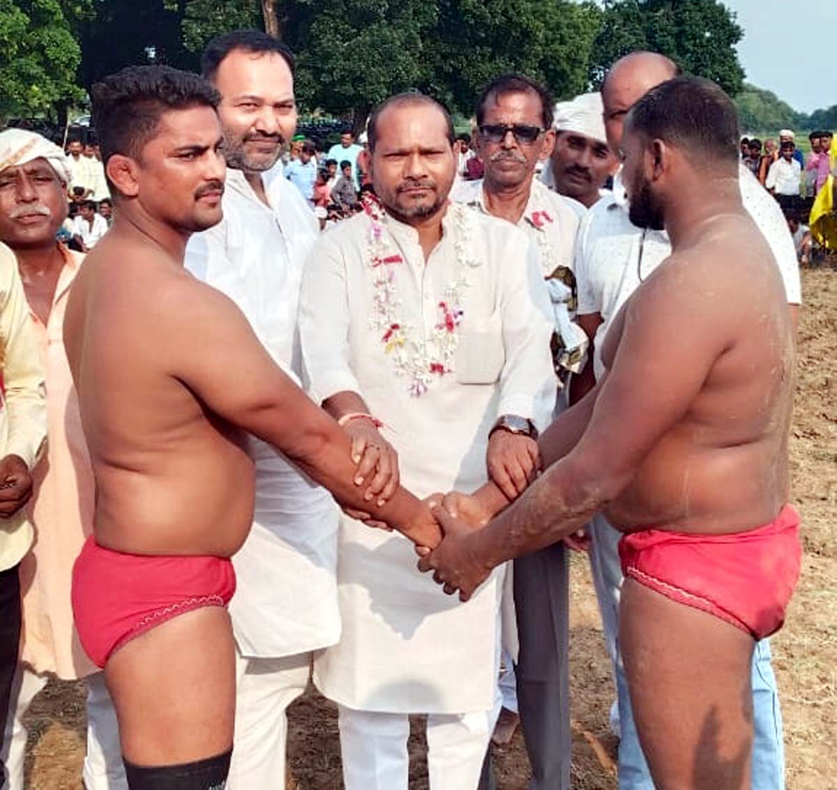 पहलवानों का हाथ मिलावाकर कुश्ती शुरू कराते अतिथि
